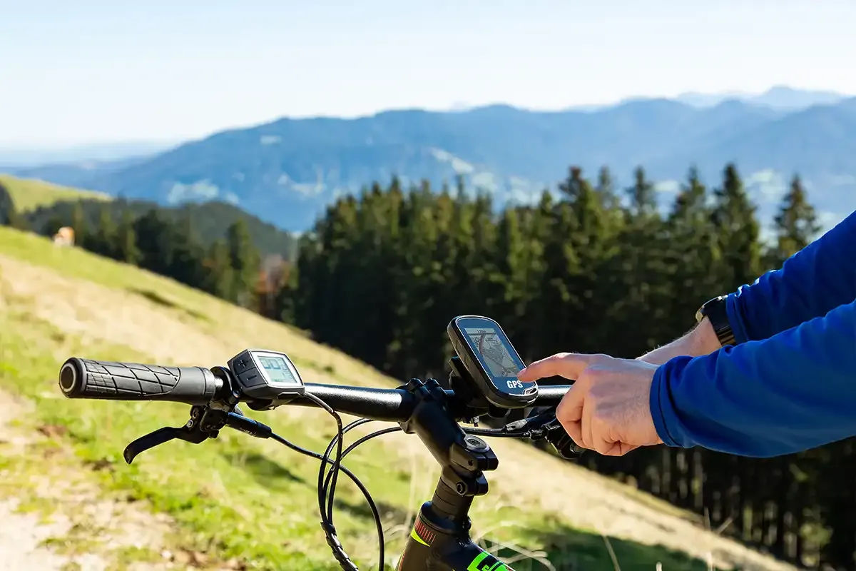 Fahrradlenkergestell, an dem ein Navigationsgerät befestigt ist, während eine Person mit dem Finger darauf zeigt.