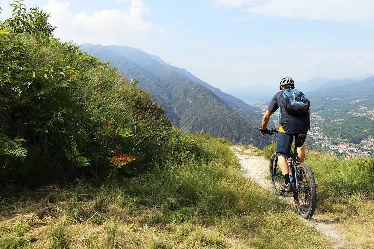Ein Mann fährt mit einem Mountainbike über einen schmalen Schotterweg in den Bergen.