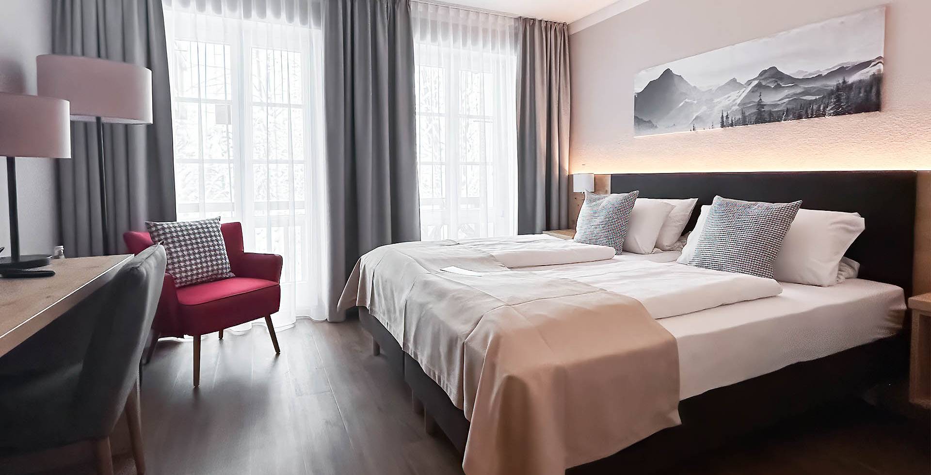 Hotelzimmer im Berghotel Hammersbach mit moderner Ausstattung und lichtdurchfluteter Fensterfront.