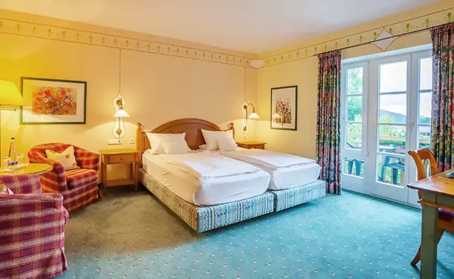 Komfort Doppelzimmer mit Doppelbett, Holzmöbeln und Sitzecke für einen gemütlichen Aufenthalt.