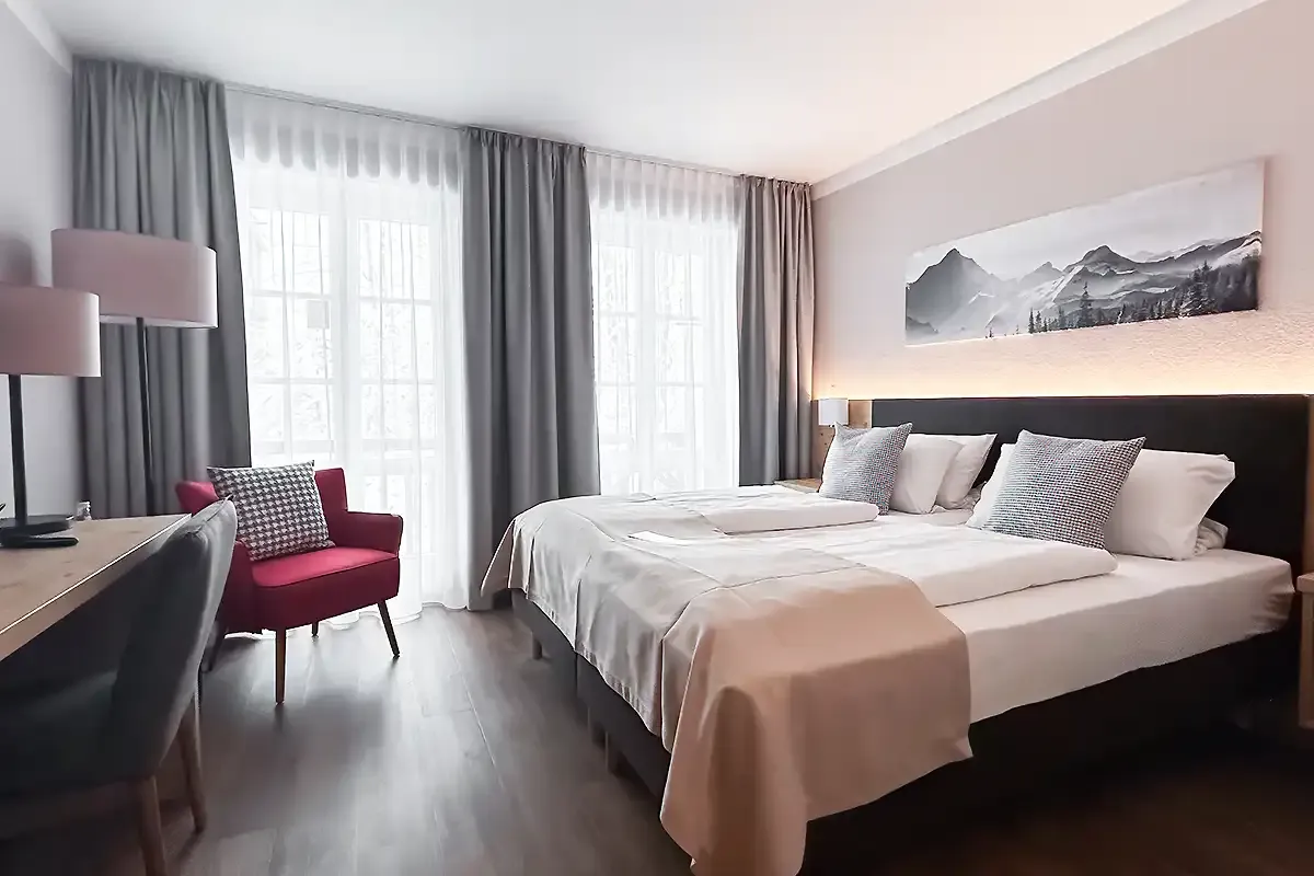 Hotelzimmer im Berghotel Hammersbach mit moderner Ausstattung und großen Doppelbett.