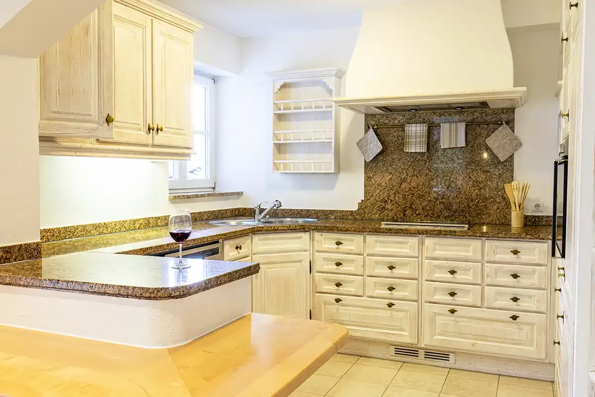 Große und helle Küche im Chalet mit Steinarbeitsplatte, Dunstabzugshaube, Spüle und Backofen für den Backspaß.