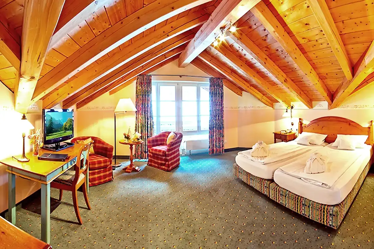 Großes Hotelzimmer unterm Dach mit Holzbalken und Doppelbett im Berghotel Hammersbach.