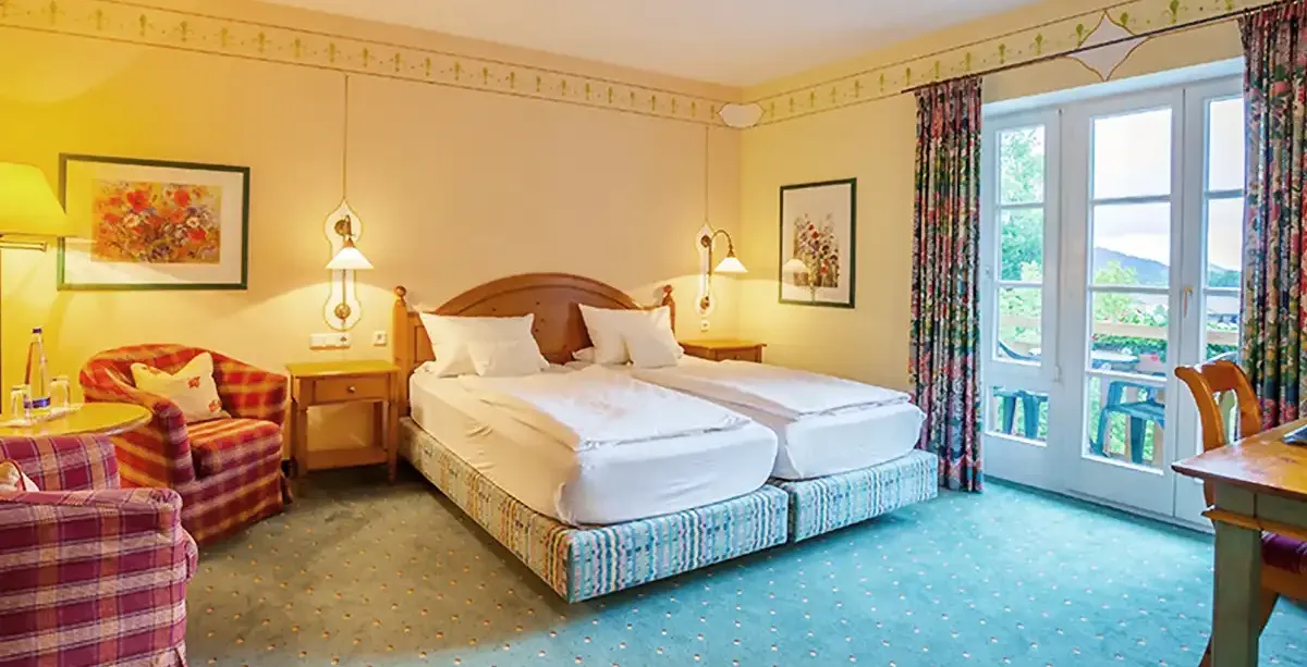 Komfort Doppelzimmer mit Doppelbett, Holzmöbeln und Sitzecke für einen gemütlichen Aufenthalt.