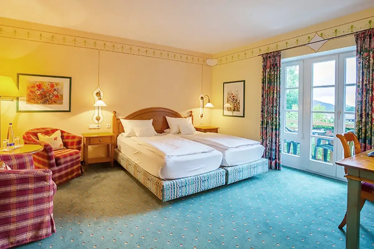 Komfort Doppelzimmer mit Doppelbett, Holzmöbeln und Sitzecke für einen gemütlichen Aufenthalt.